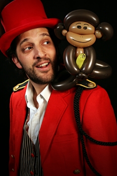 A ballon modeller with a ballon monkey on his shoulder by Totally Twisted Balloons.
